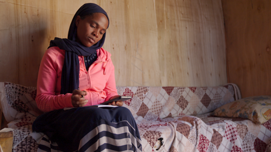 Young woman sits on sofa and looks at phone